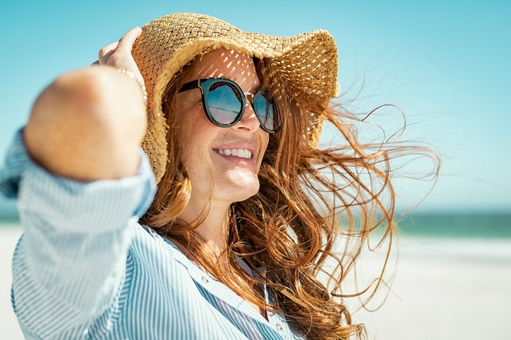 kobieta na plaży w kapeluszu i okularach przeciwsłonecznych
